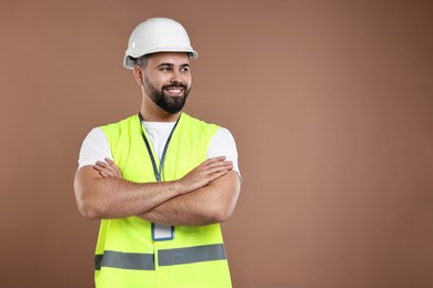 Photo of Engineer with hard hat and badge on brown background, space for text