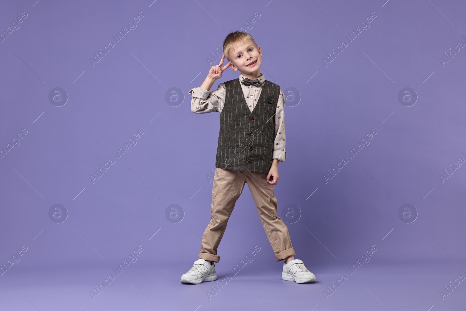 Photo of Happy little boy dancing on violet background