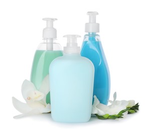 Dispensers of liquid soap and beautiful flowers on white background