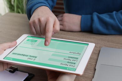 Electronic signature. Man using tablet at wooden table, closeup