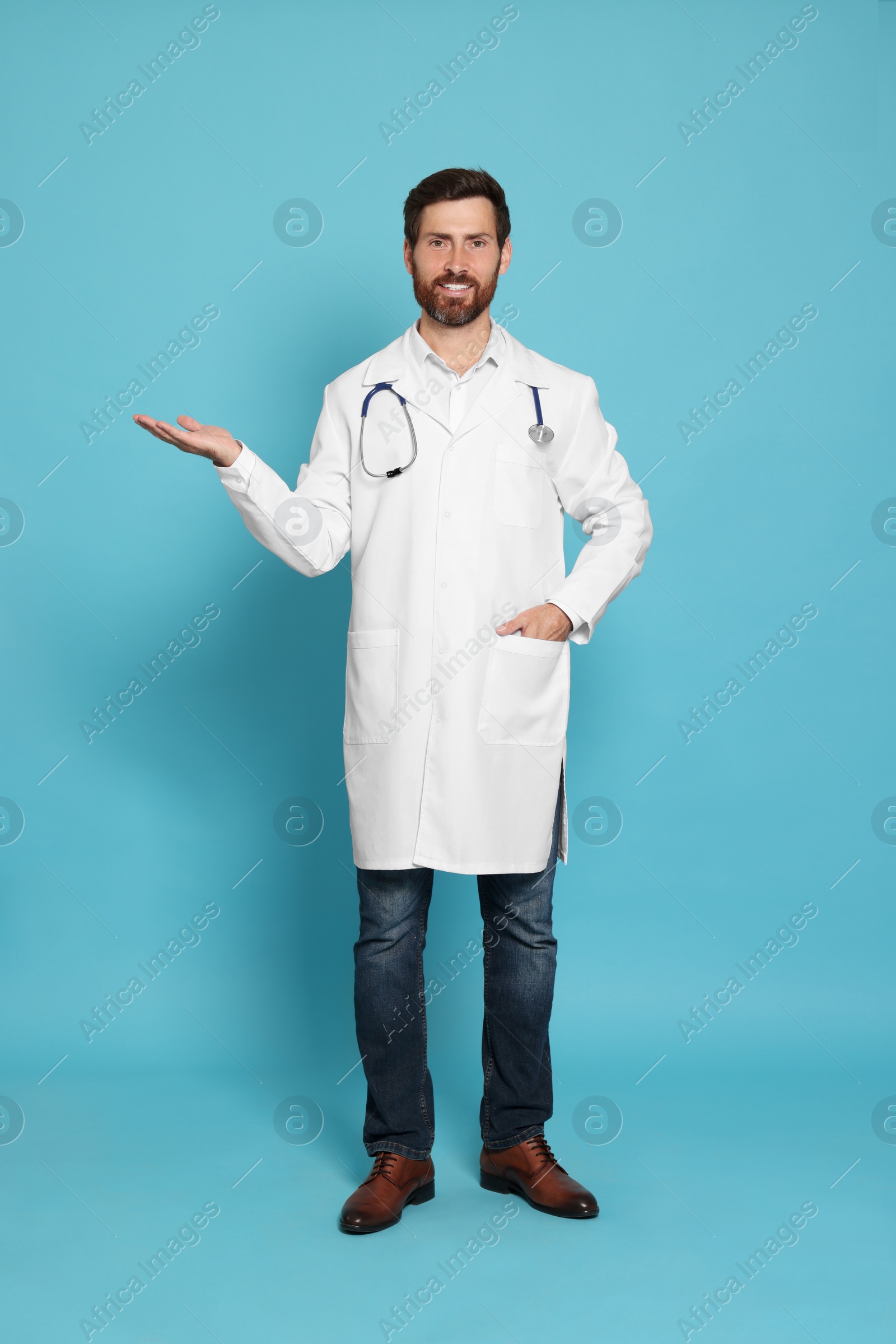 Photo of Full length portrait of doctor with stethoscope on light blue background