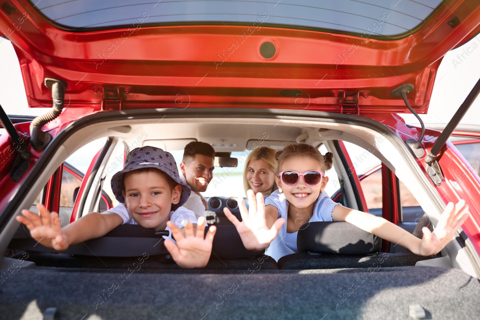 Photo of Happy family in car on sunny summer day, view through open trunk