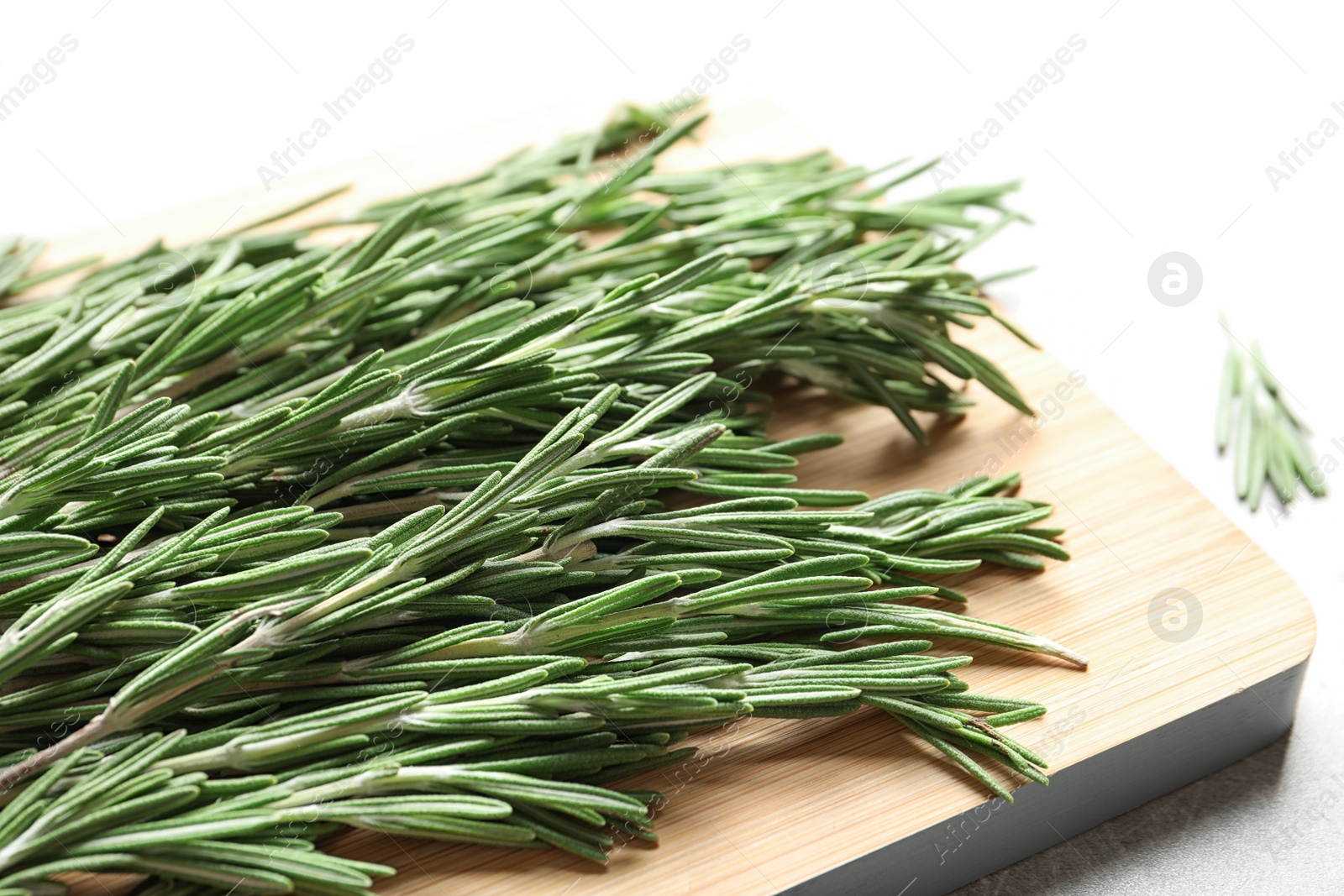 Photo of Wooden board with fresh rosemary twigs on table, closeup