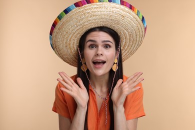 Photo of Surprised young woman in Mexican sombrero hat on beige background