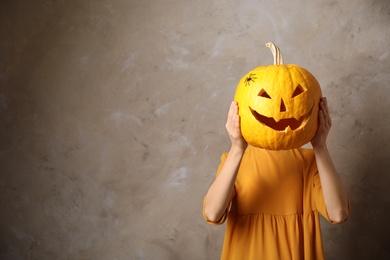 Photo of Woman with pumpkin head against beige background, space for text. Jack lantern - traditional Halloween decor