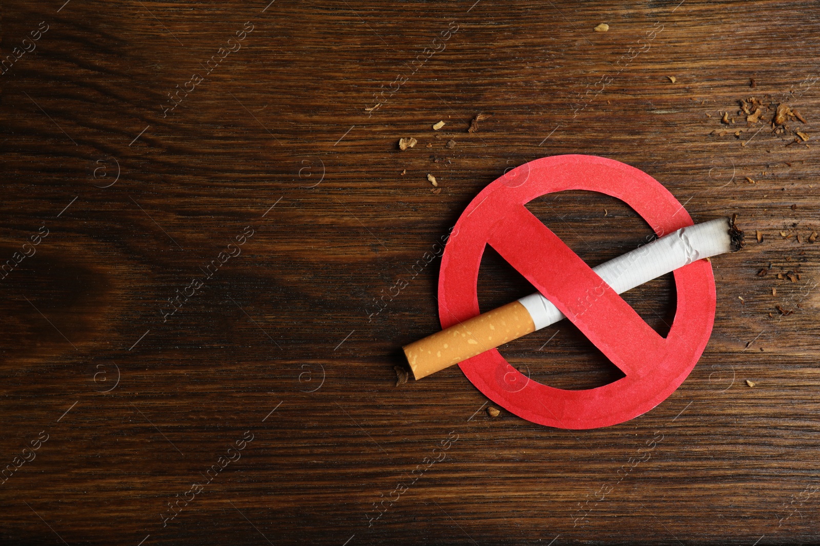 Photo of Cigarette with prohibition sign and space for text on wooden table, top view. Quitting smoking concept