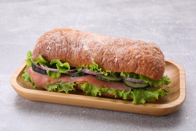 Photo of Delicious sandwich with fresh vegetables and salmon on light gray table