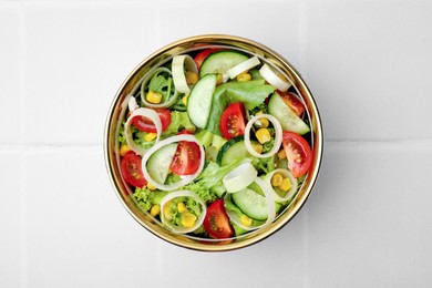 Photo of Bowl of tasty salad with leek, tomatoes and cucumbers on white tiled table, top view