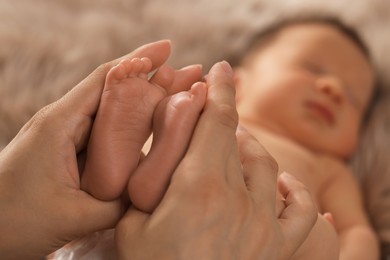 Photo of Mother holding her newborn baby, closeup view on feet. Lovely family