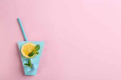 Creative lemonade layout with lemon slice, mint and ice cubes on pink background, top view. Space for text