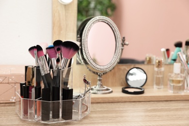 Photo of Organizer with cosmetic products for makeup on table near mirror. Space for text