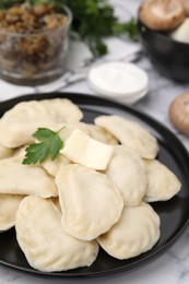 Photo of Delicious dumplings (varenyky) with tasty filling, butter and parsley on white table, closeup