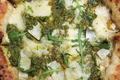 Delicious pizza with pesto, cheese and arugula as background, top view