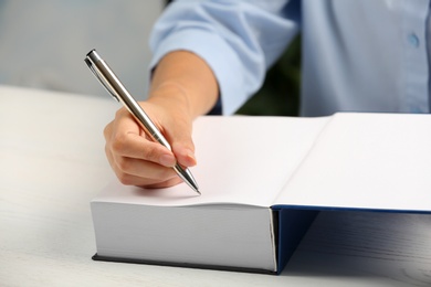 Writer signing autograph in book at table, closeup