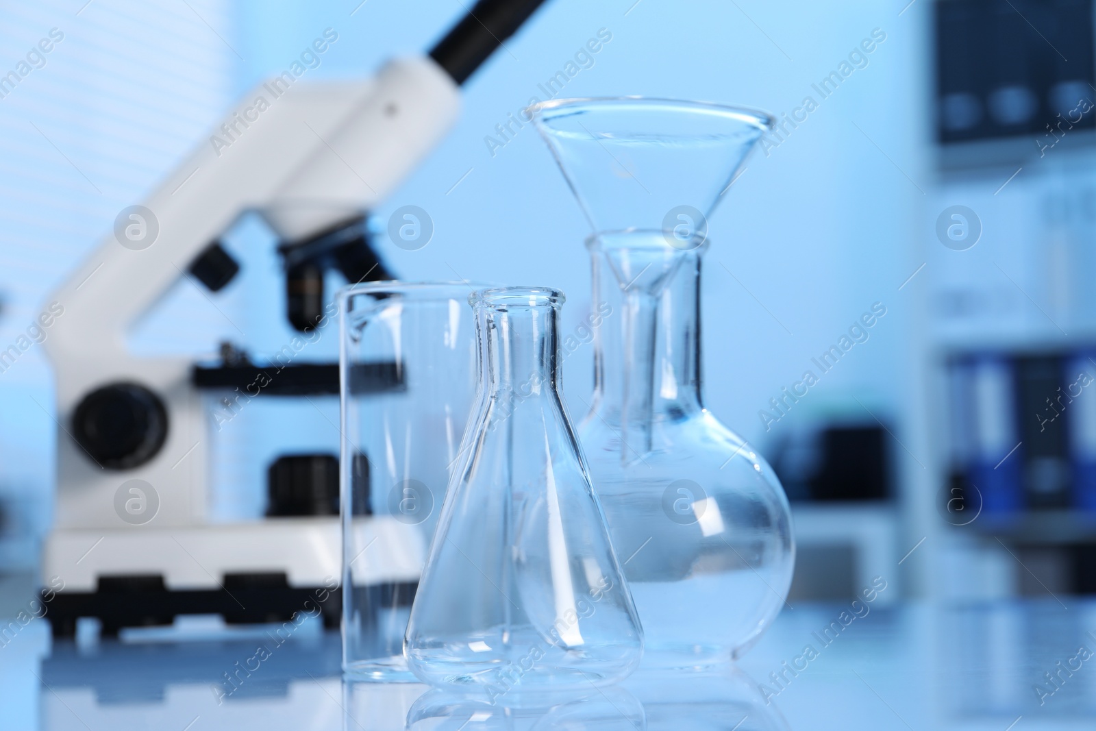 Photo of Laboratory analysis. Different glassware and microscope on white table indoors