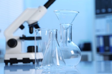 Photo of Laboratory analysis. Different glassware and microscope on white table indoors