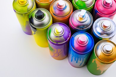 Photo of Used cans of spray paints on white background, above view. Graffiti supplies