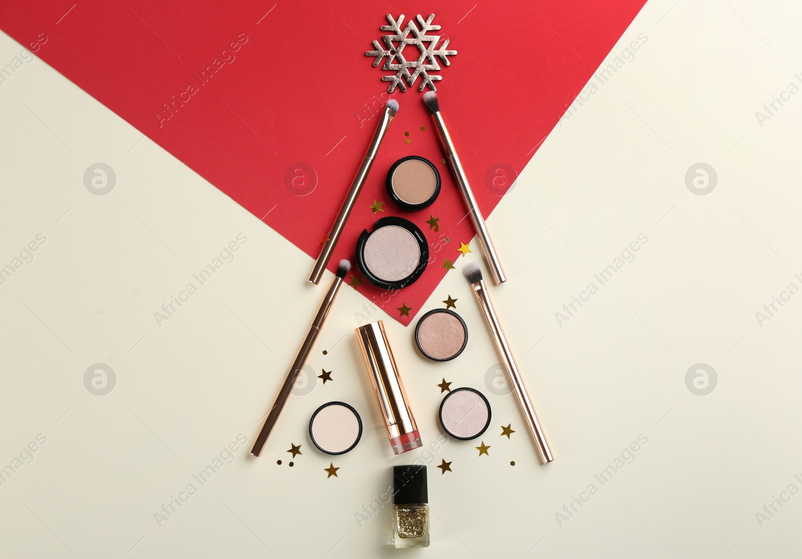 Photo of Christmas tree shape of decorative cosmetic products on color background, flat lay. Winter care