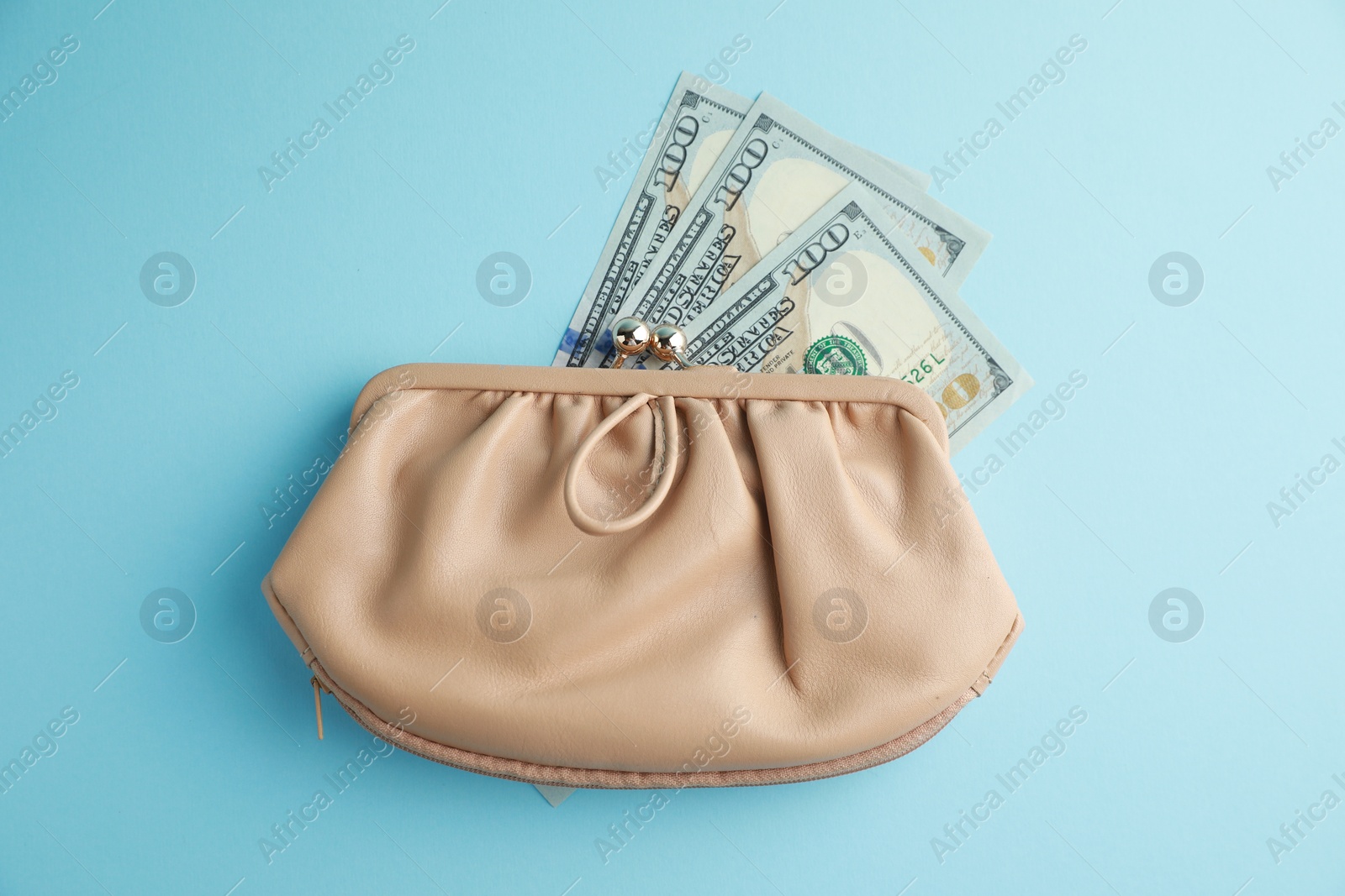 Photo of One stylish leather purse with money on light blue background, top view