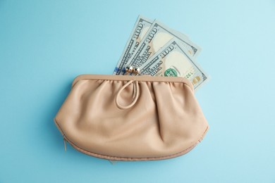 One stylish leather purse with money on light blue background, top view