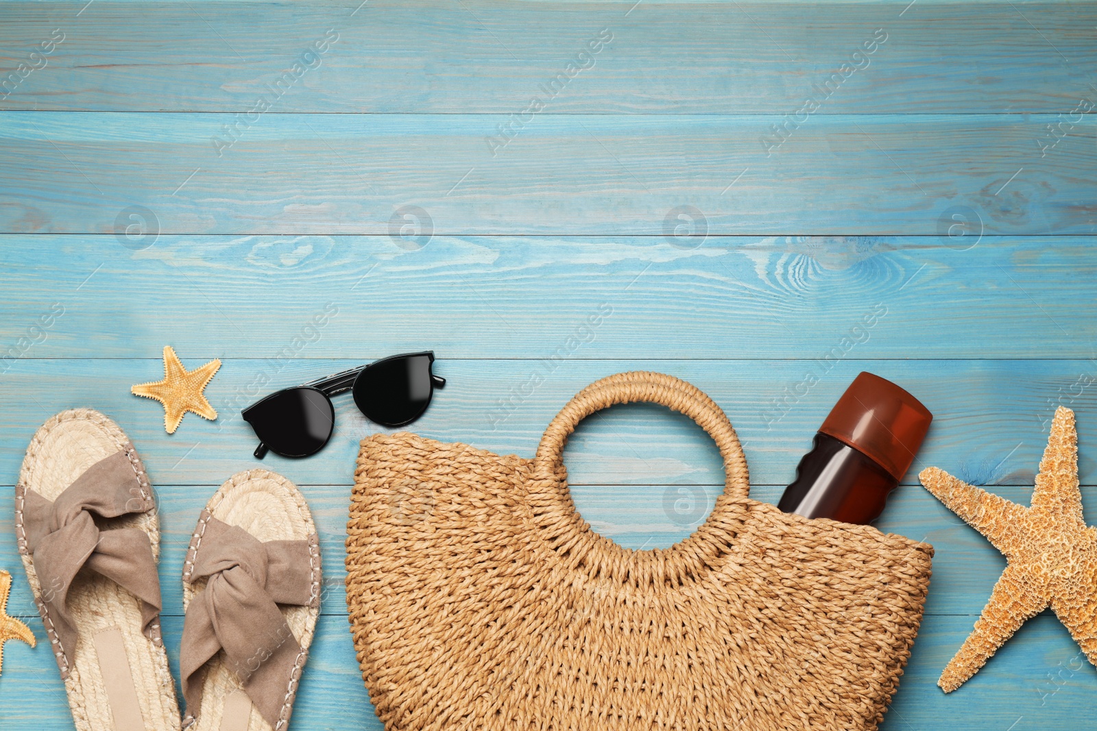 Photo of Stylish bag and beach accessories on blue wooden background, flat lay. Space for text