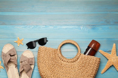 Stylish bag and beach accessories on blue wooden background, flat lay. Space for text