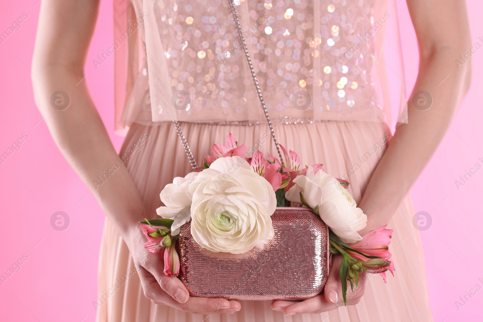 Photo of Woman holding elegant handbag with spring flowers on pink background, closeup