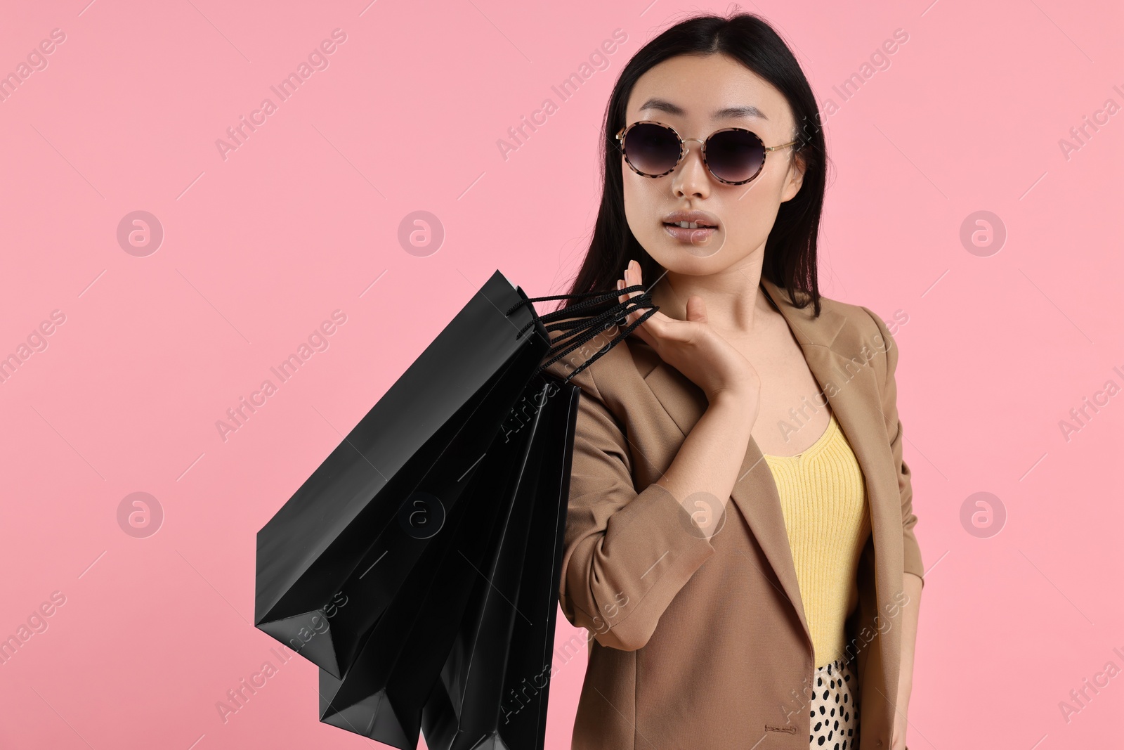 Photo of Beautiful woman with shopping bags on pink background. Space for text