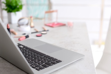 Photo of Laptop and makeup products for woman on table