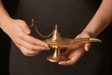 Photo of Woman rubbing magical Aladdin lamp, closeup