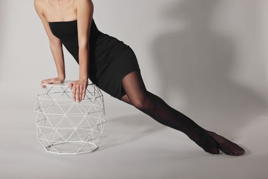 Woman with beautiful long legs wearing black tights on light background, closeup