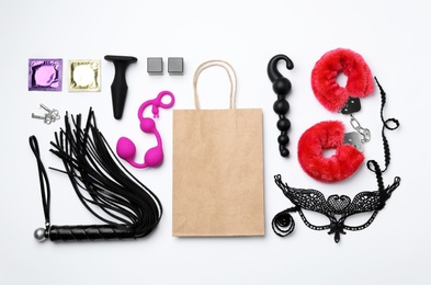 Photo of Shopping bag and different sex toys on white background, top view