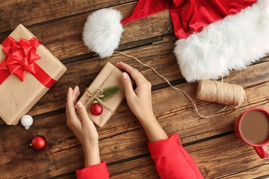Photo of Woman with Christmas gift boxes at wooden table, top view