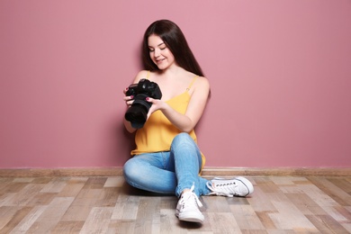 Female photographer with professional camera near color wall indoors