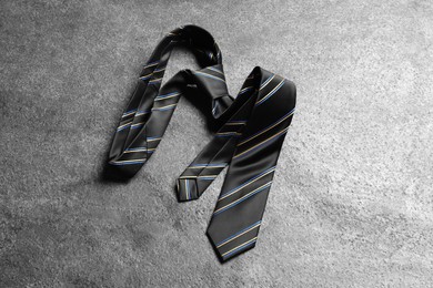 Photo of One striped necktie on grey textured background, top view