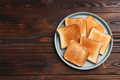 Photo of Slices of tasty toasted bread on wooden table, top view. Space for text