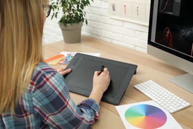 Professional retoucher working on graphic tablet at desk, closeup