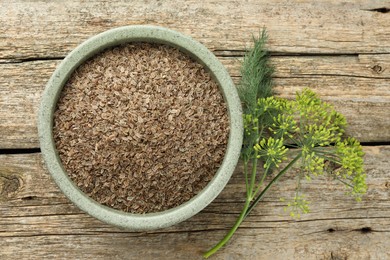 Photo of Dry seeds and fresh dill on wooden table, flat lay