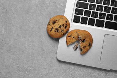 Photo of Chocolate chip cookies and laptop on light grey table, flat lay. Space for text