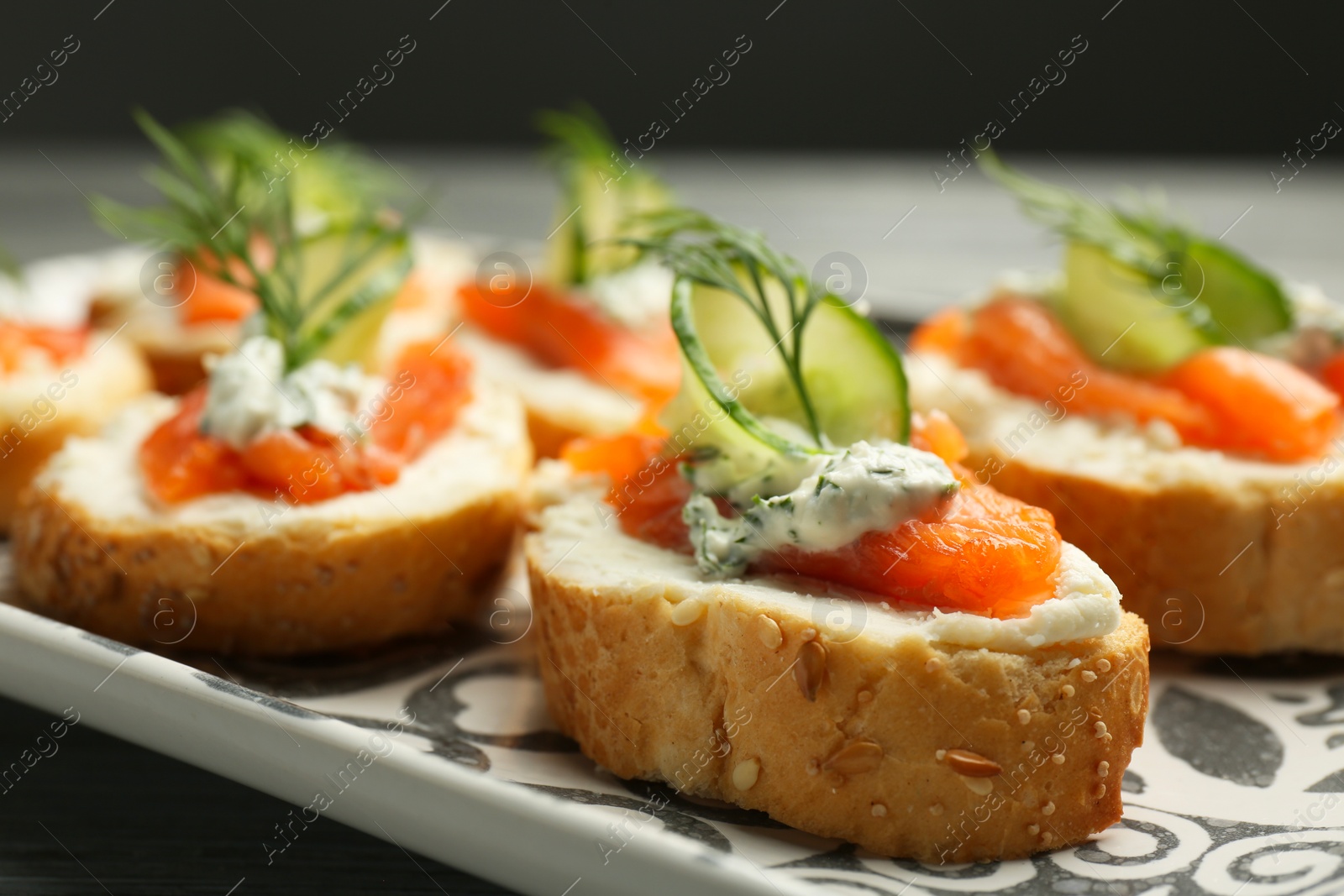 Photo of Tasty canapes with salmon, cucumber, cream cheese and dill on table, closeup