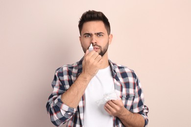 Man using nasal spray on beige background