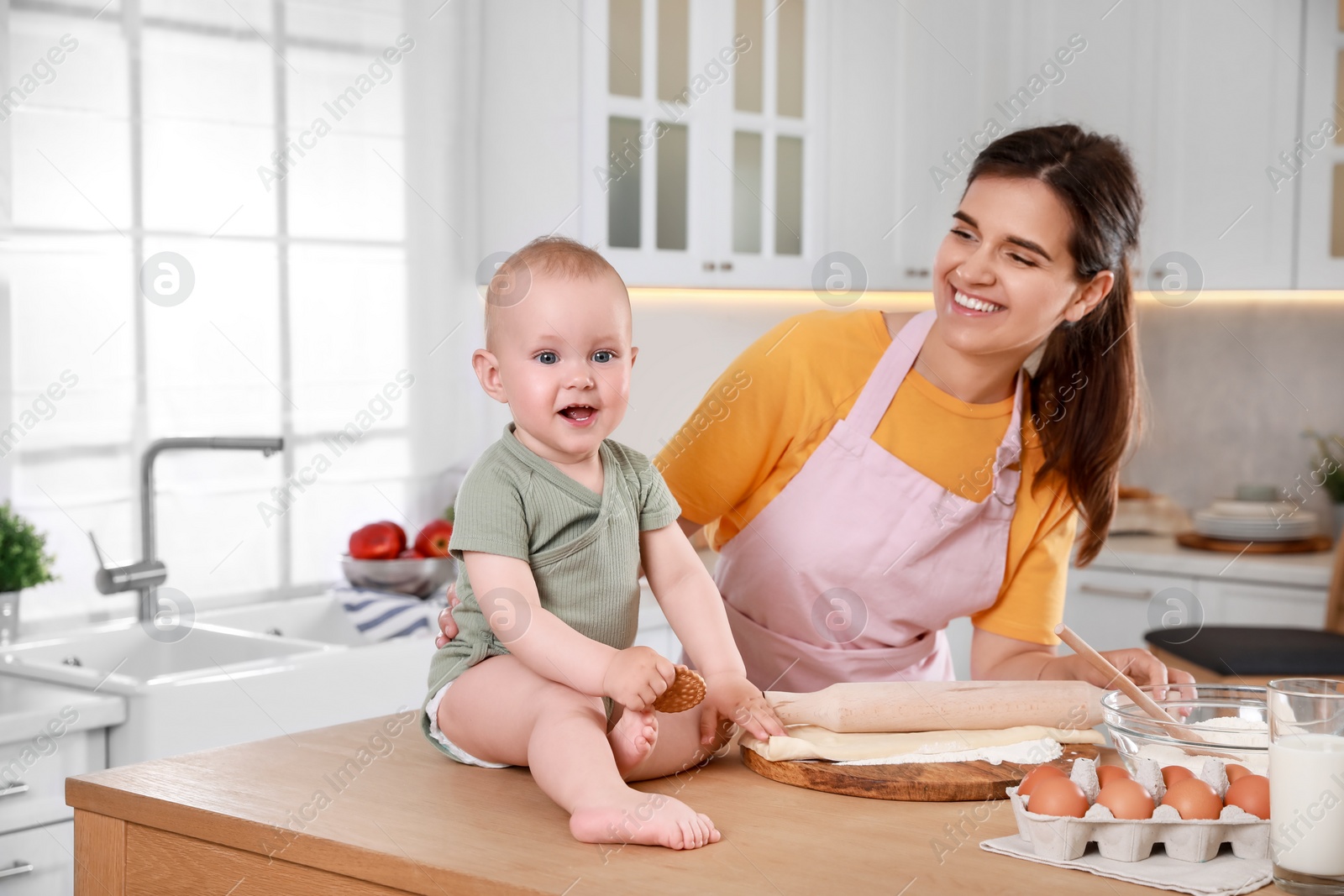 Photo of Happy young woman and her cute little baby cooking together in kitchen