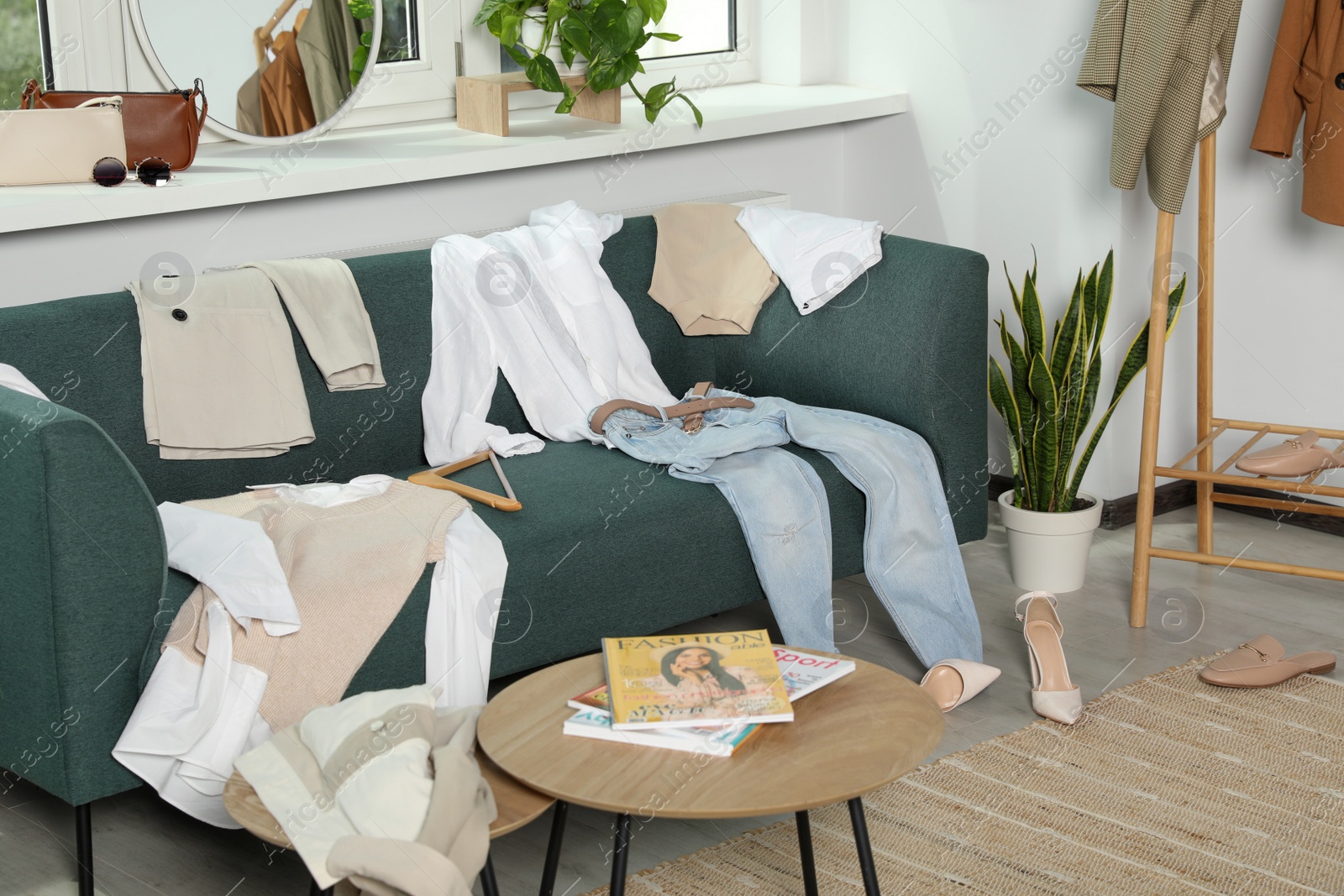 Photo of Messy pile of clothes on sofa and shoes in living room