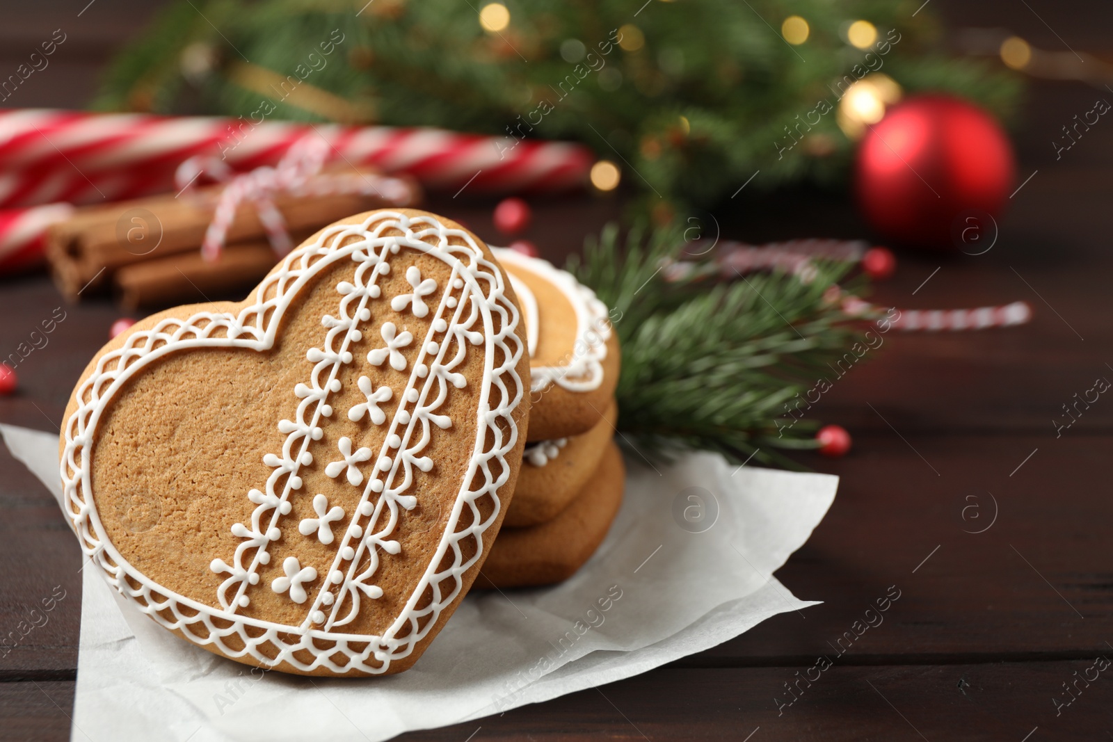 Photo of Tasty heart shaped gingerbread cookies and Christmas decor on wooden table, closeup. Space for text