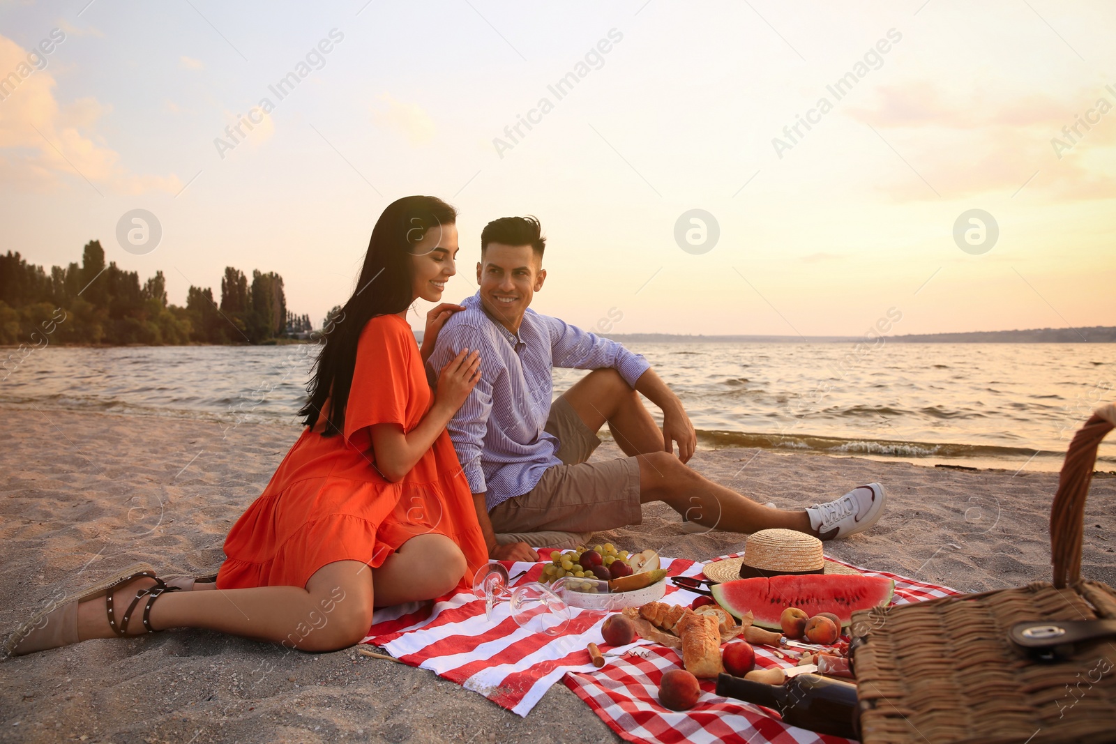 Photo of Lovely couple having picnic near river at sunset