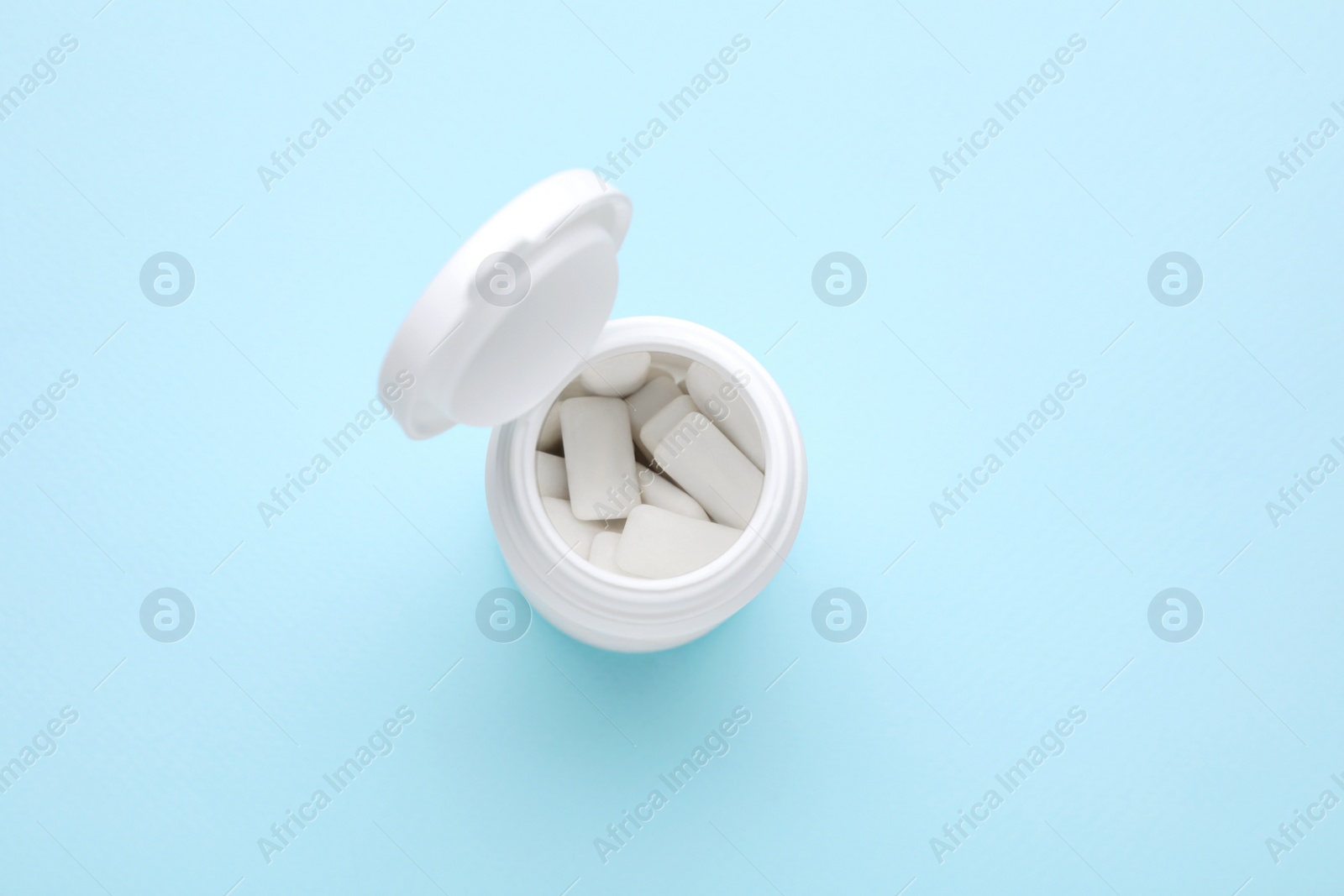 Photo of Jar with chewing gums on light blue background, top view