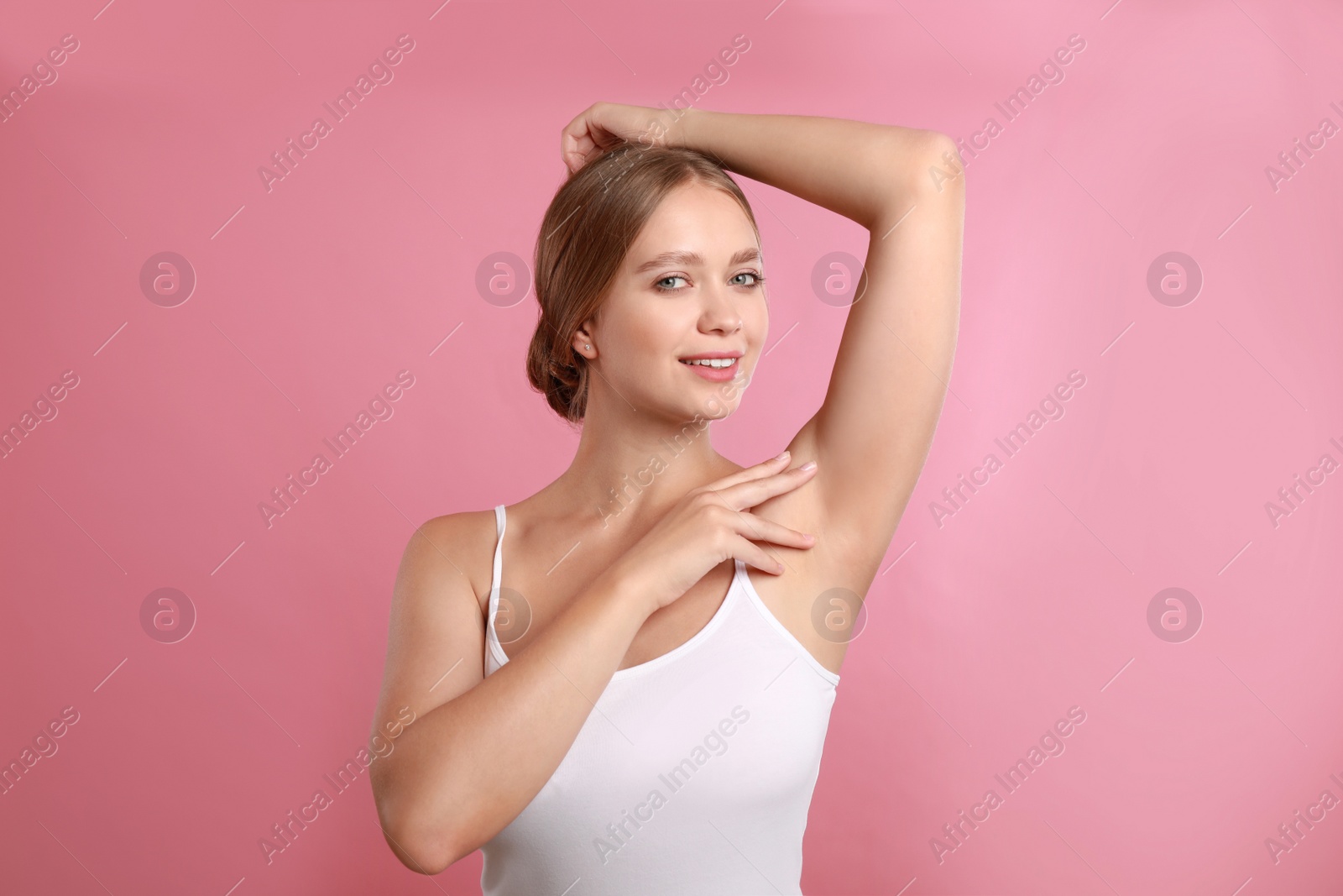 Photo of Young woman with smooth clean armpit on pink background. Using deodorant