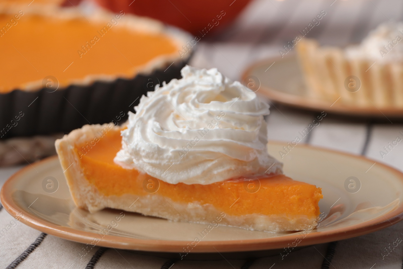 Photo of Piece of fresh homemade pumpkin pie with whipped cream on table