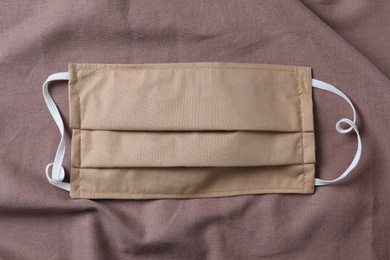 Photo of Homemade protective mask on brown fabric, top view