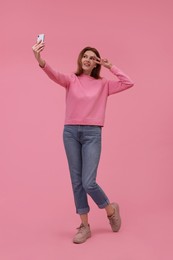 Photo of Beautiful woman taking selfie on pink background